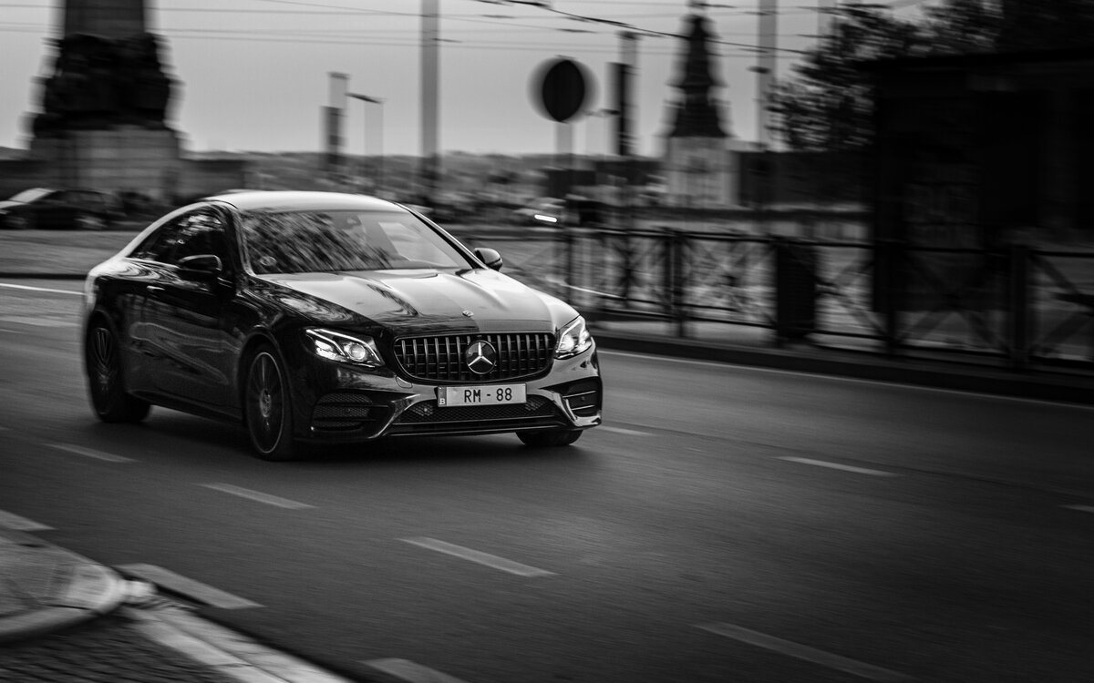 Berline noire en mouvement, ambiance urbaine en noir et blanc par Luca Struglia